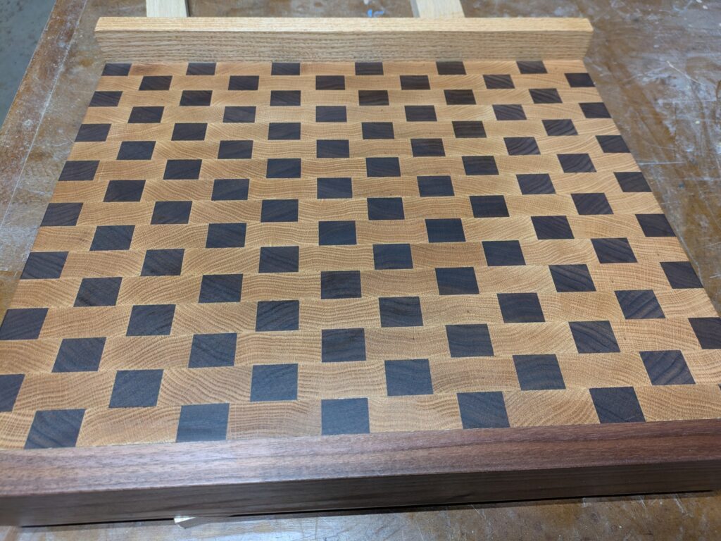 Oak, cherry and black walnut cutting board with counter-holding edges.